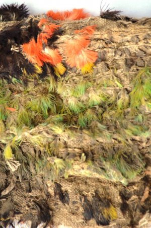 Небольшой резной деревянный предмет и кусок ткани с перьевым украшением найдены в археологическом комплексе Пачакамак возле Лимы. Фото - Министерство культуры Перу / cultura.gob.pe