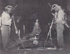 два индейца-яки, вооруженные луками, в почетном караул у статуи Христа