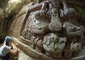 Археолог Аня Шетлер очищает надпись под древним фризом из штука, который был недаво раскопан в городище майя Хольмуль (Гватемала). Солнечный свет из входа в прорытый туннель освещает ноги правителя, сидящего на голове майяского духа горы. Фото - Франсиско Эстрада-Белли.